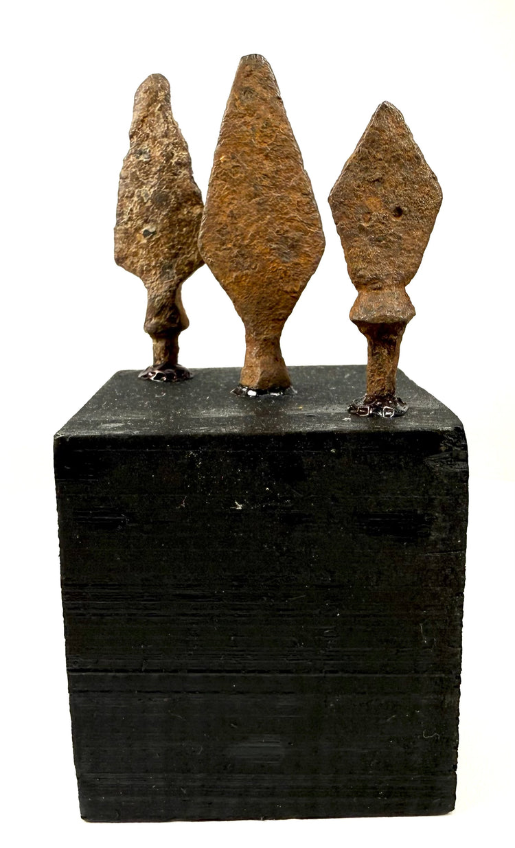 Frontal view of hand-forged iron weapon tips showing heavy corrosion and surviving tangs
