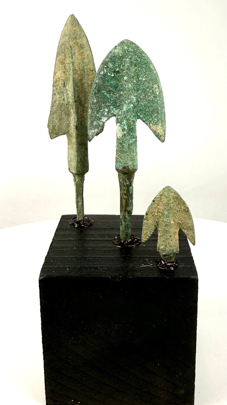 Full shot of bronze arrowhead collection on cubic pedestal