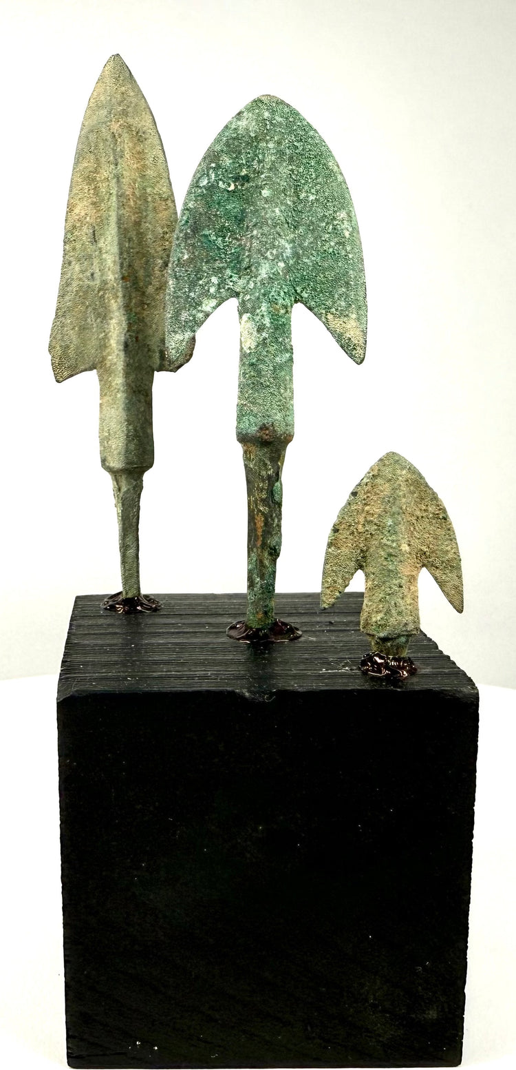 Ancient bronze arrowheads and winged projectile points on display stand