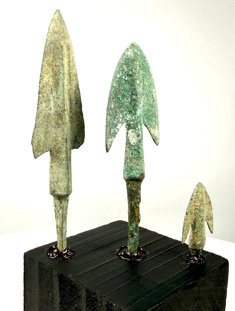 Side profile of weathered bronze spearheads on textured base