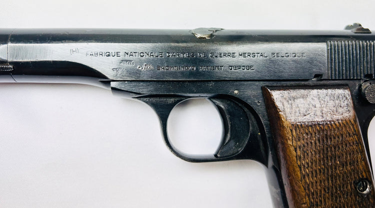 Close-up of WWII-era Belgian Browning FN Model 1922 pistol showing Fabrique Nationale Herstal Belgium markings and walnut grip on white background.