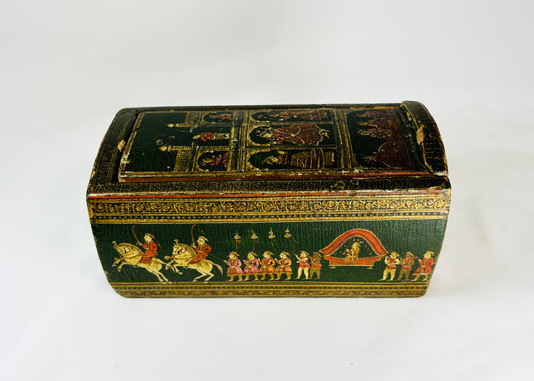 19th-century Indian Ganjifa storage box with hand-painted procession scene on a green background, photographed on a white backdrop.