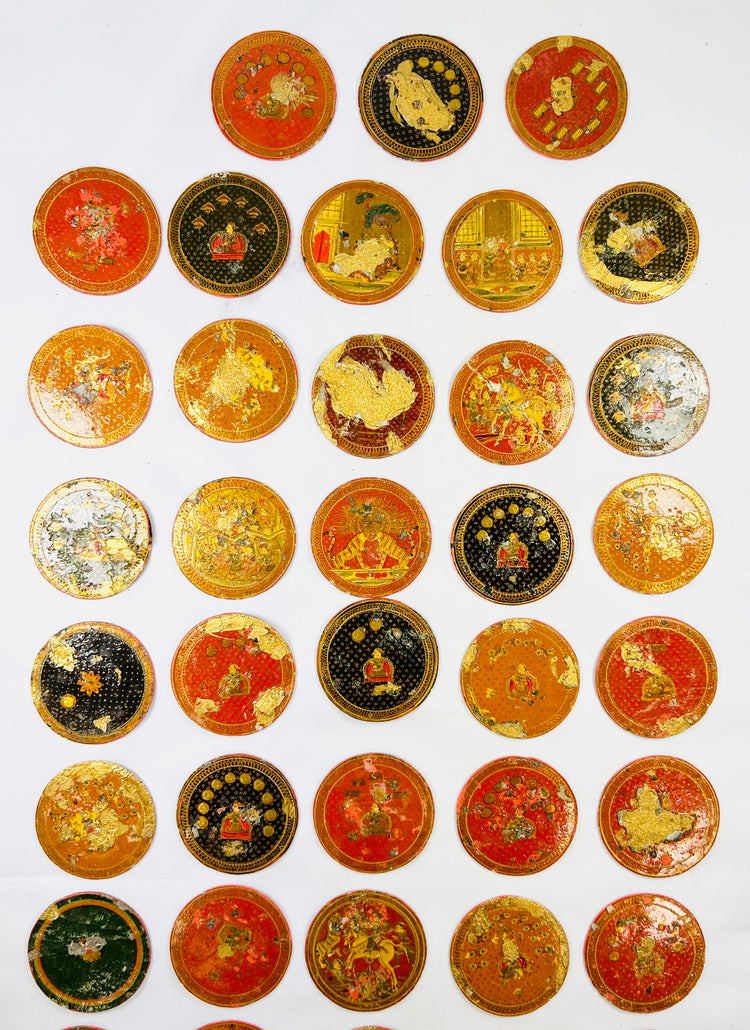 Close-up layout of antique Indian Ganjifa playing cards featuring miniature artwork and lacquered circular designs, displayed on a white background.