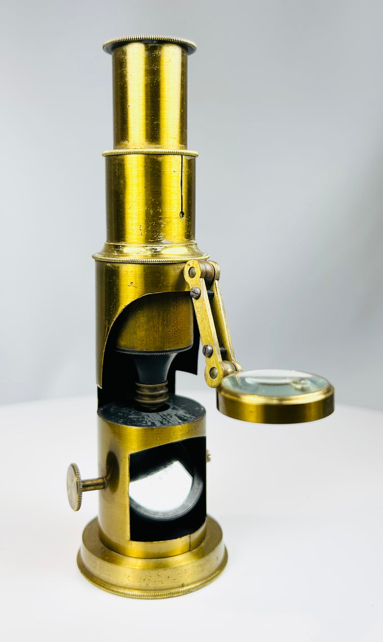 19th century portable brass microscope with mirror base and compact scientific design