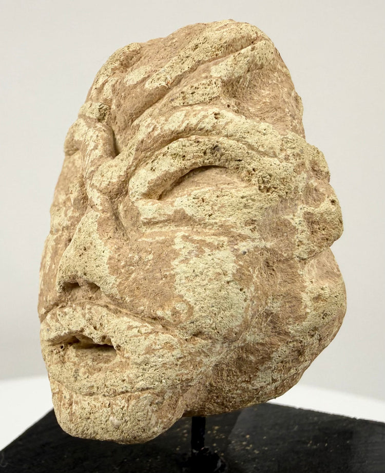 Historic Mesopotamian-style idol head displaying a broad flat nose, wide mouth, and natural surface erosion.