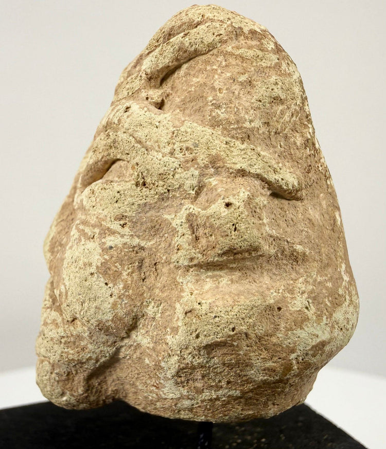 Mesopotamian style stone sculpture with deep-set eyes and broad nose on black stand