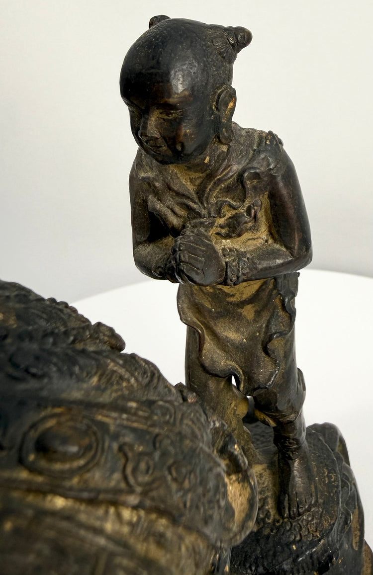 Close-up of small standing attendant figure beside antique bronze sculpture base
