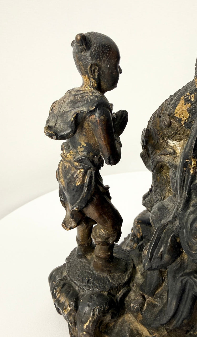 Macro shot of praying attendant figure on textured pedestal of bronze statue