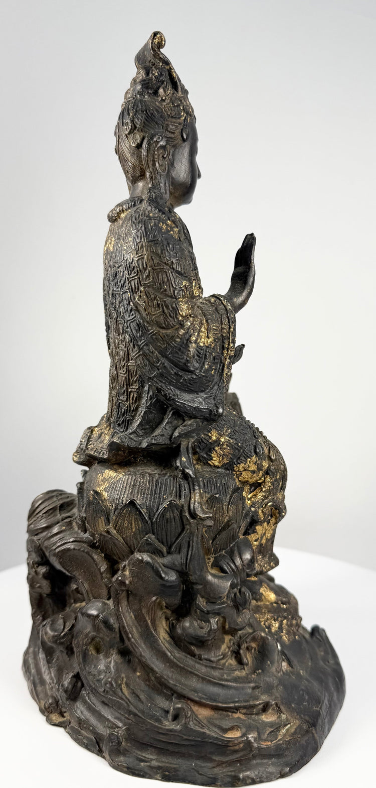 Side profile of seated Guanyin Bodhisattva in meditation on lotus pedestal