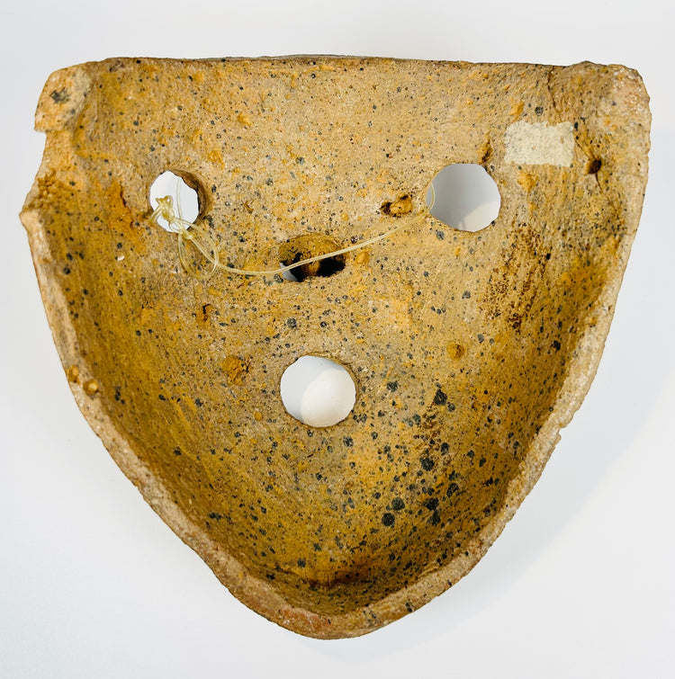 Mesoamerican clay mask with bold features and burial encrustation