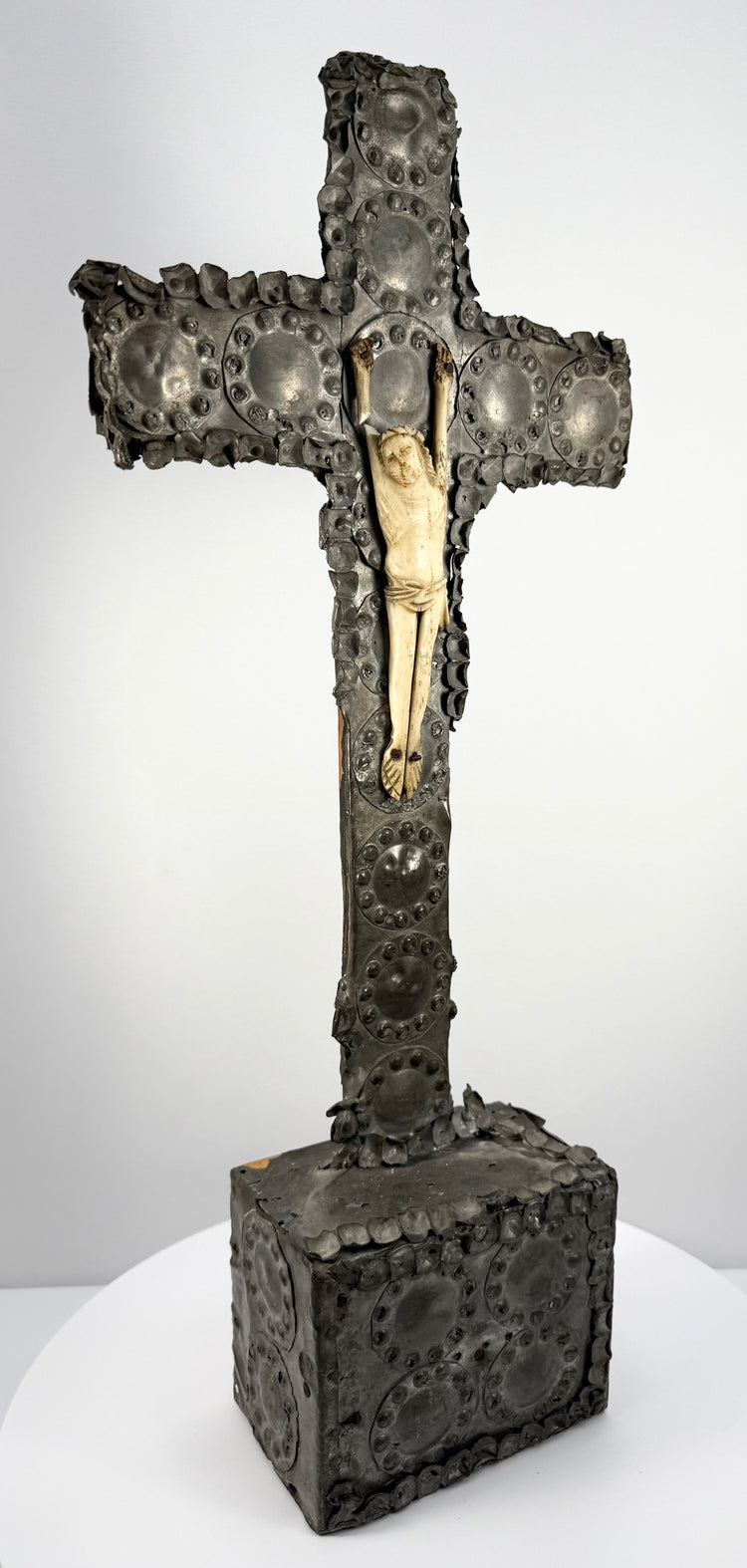 Three-quarter view of hand-carved wood and tin colonial crucifix on pedestal