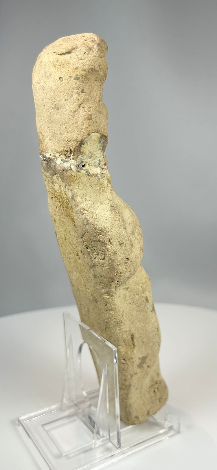 Ancient terracotta statue with stylized anatomy and worn surface