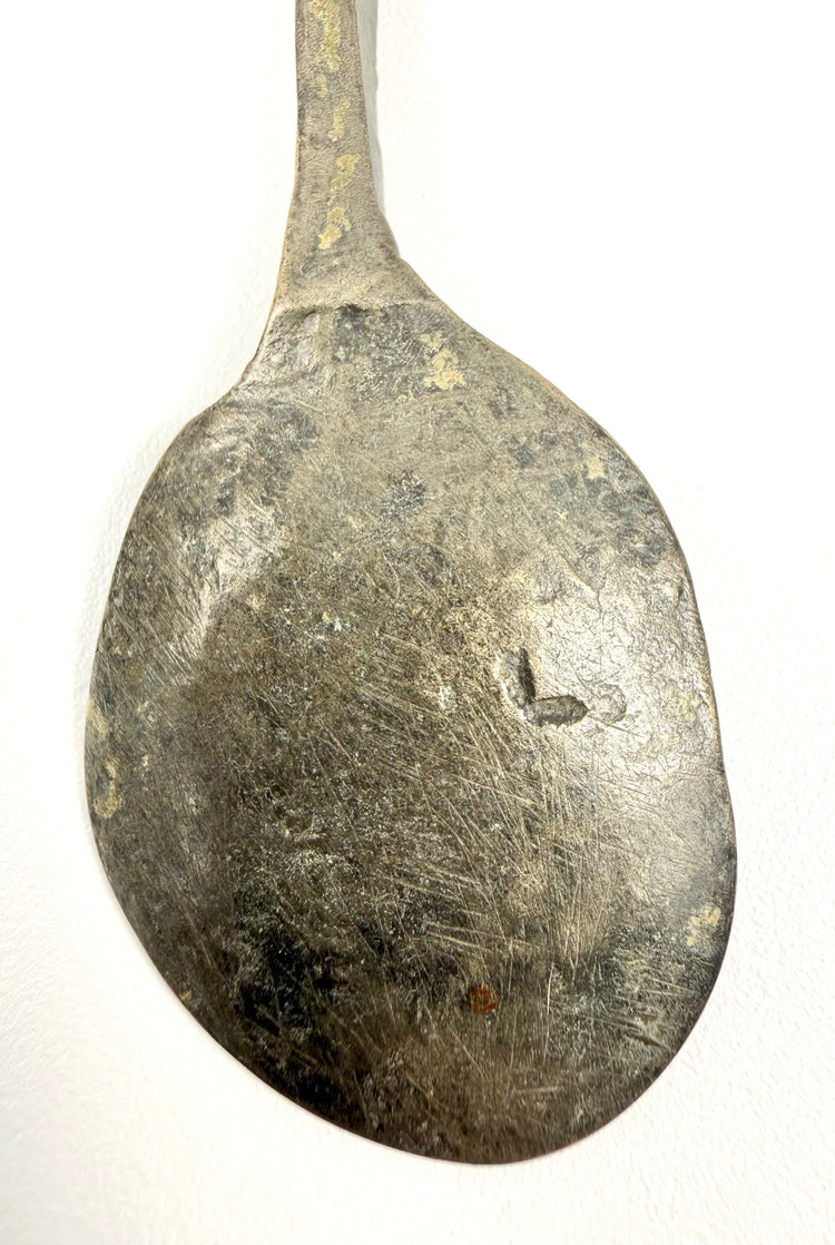 Detailed view of an ancient Roman dining utensil featuring dark green and brown bronze patination.