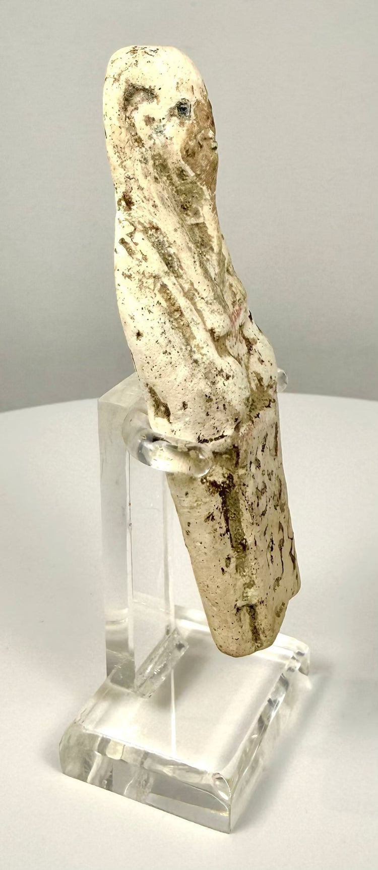 Ancient Egyptian funerary figure with an irregular lower edge, visible surface wear, and remnants of an earlier identification label.