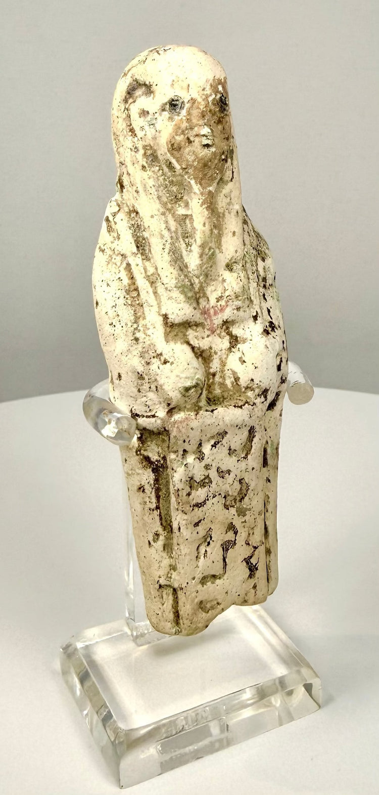 Limestone ushabti with a surviving label remnant on the reverse and areas of uneven coloration across its ancient surface.
