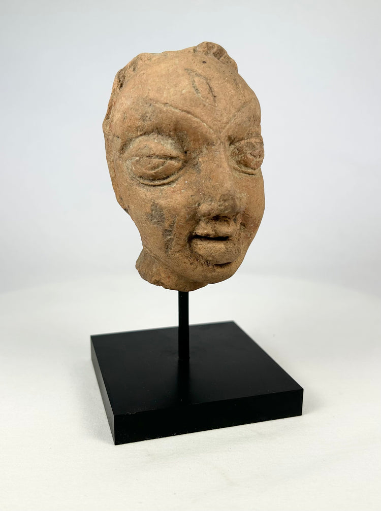 Front-right view of a Gupta-period terracotta head fragment with characteristic almond-shaped eyes.