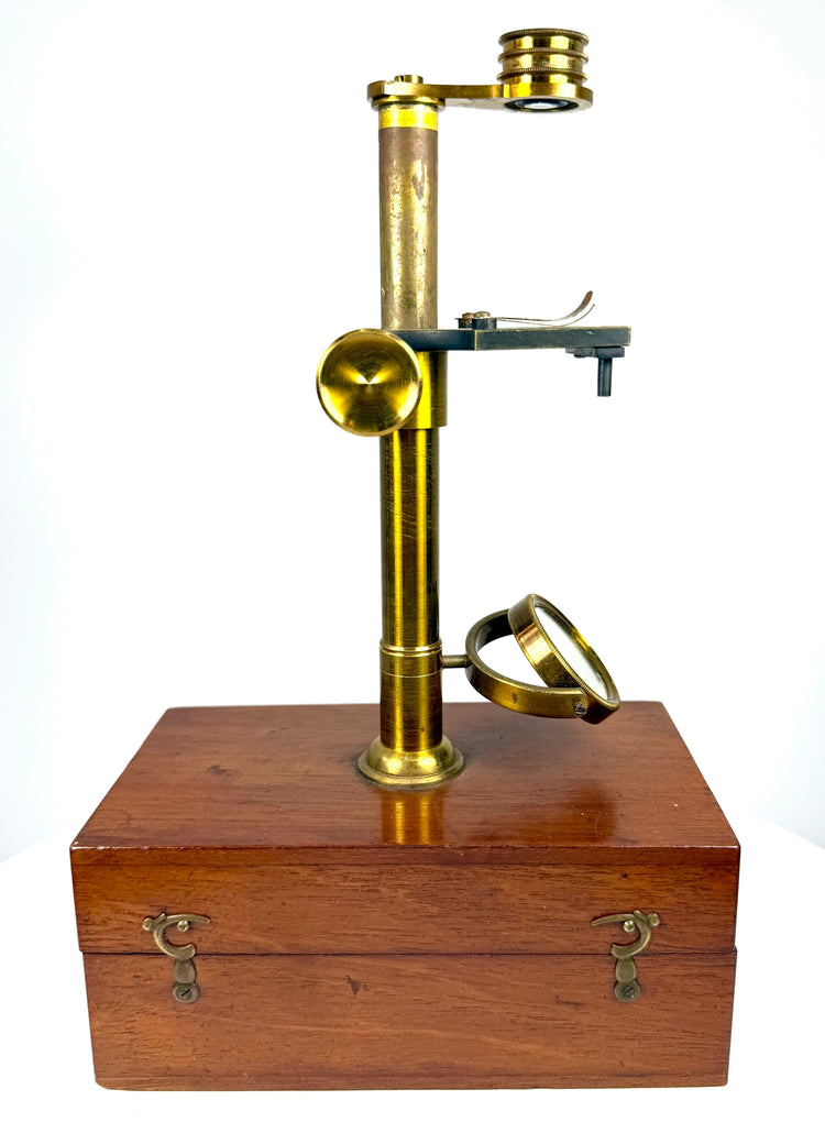 19th-century brass scientific microscope with cylindrical support pillar, rectangular specimen stage and adjustable focusing mechanism.