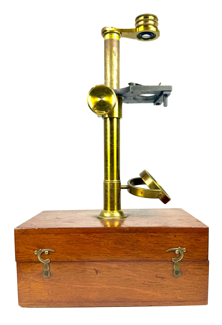 Antique brass dissecting microscope with adjustable circular focusing knob and traditional Victorian scientific instrument construction.