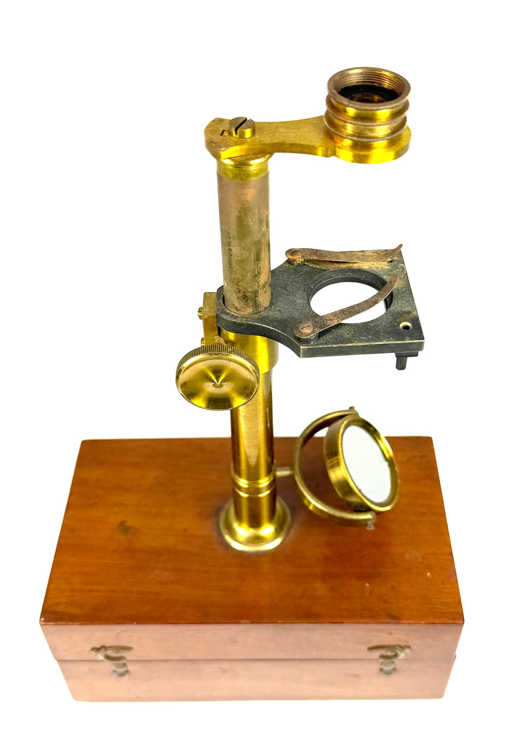 Victorian microscope specimen stage with blackened metal platform, central aperture and brass spring clips for securing specimens.
