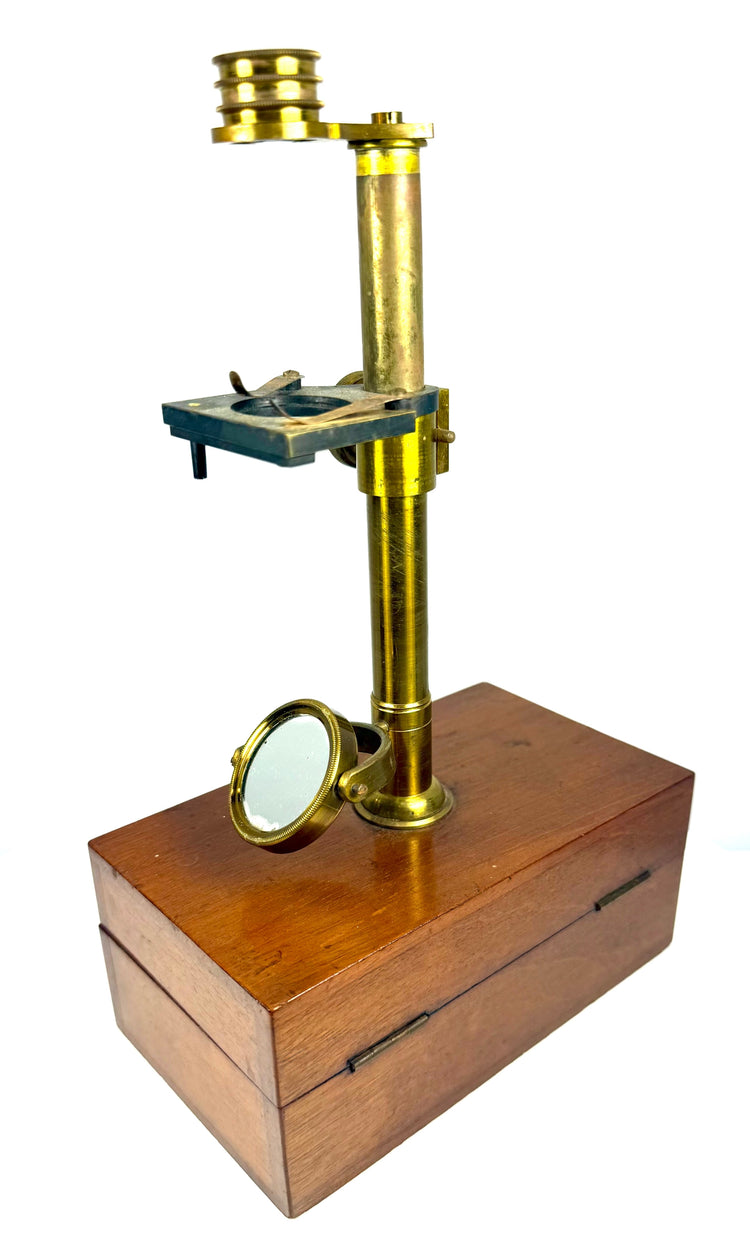 Victorian brass microscope with rotating optical mirror, finely threaded metal fittings and traditional scientific instrument components.