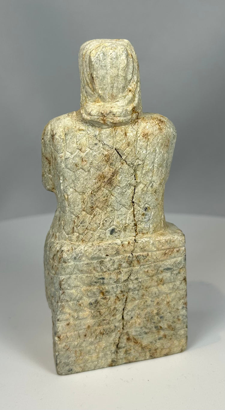 Carved stone worshipper figure with long robe and patina