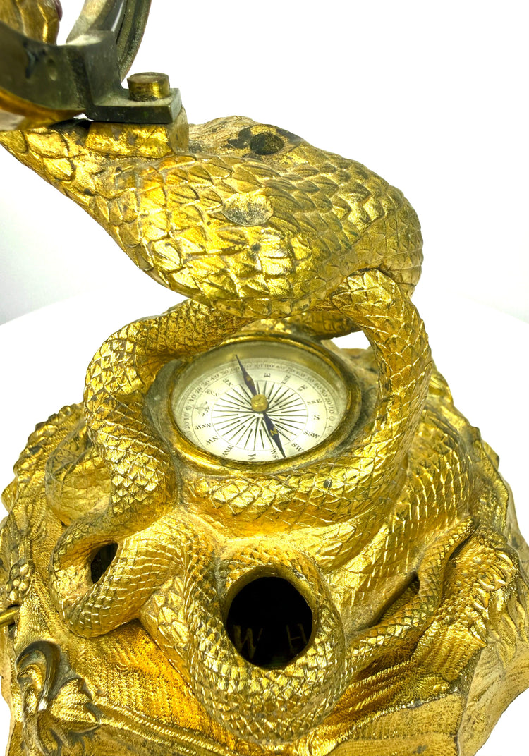 Victorian scientific desk ornament with a curved glass thermometer, graduated temperature markings, and gilt metal circular frame.