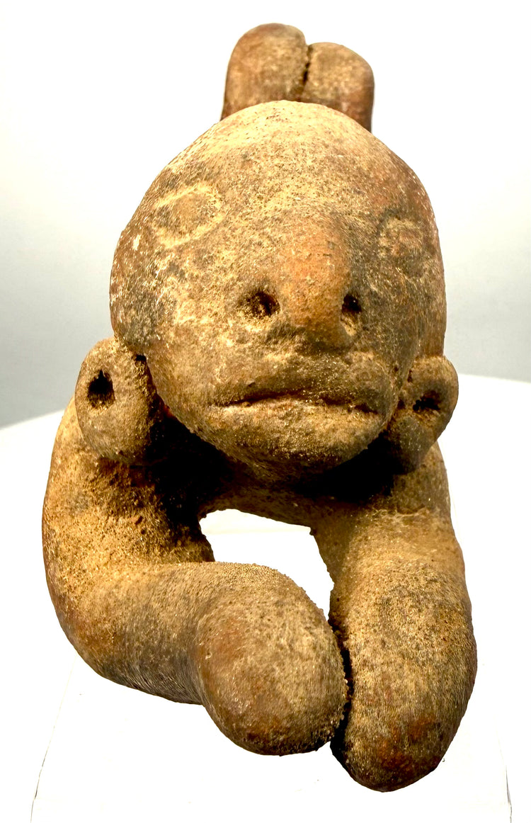 Pre-Columbian Ecuadorian-style terracotta sculpture depicting a reclining human figure with elongated torso, extended arms, and bent legs.