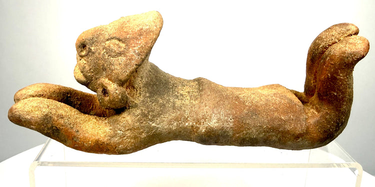 Ancient South American-style anthropomorphic sculpture featuring natural reddish-brown earthenware tones and widespread sandy surface deposits.
