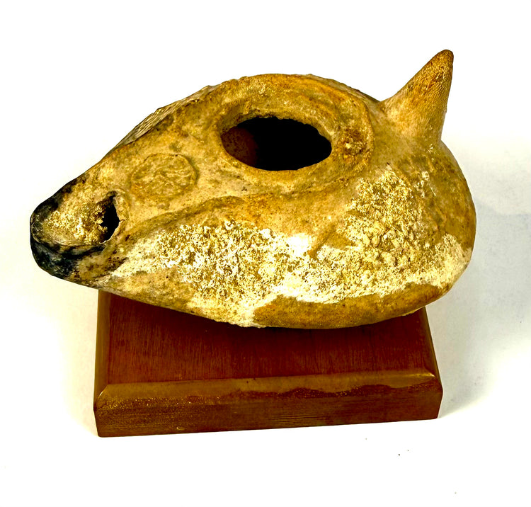 Eastern Mediterranean terracotta oil lamp with raised central filling aperture, extended nozzle, and aged earthenware surface.