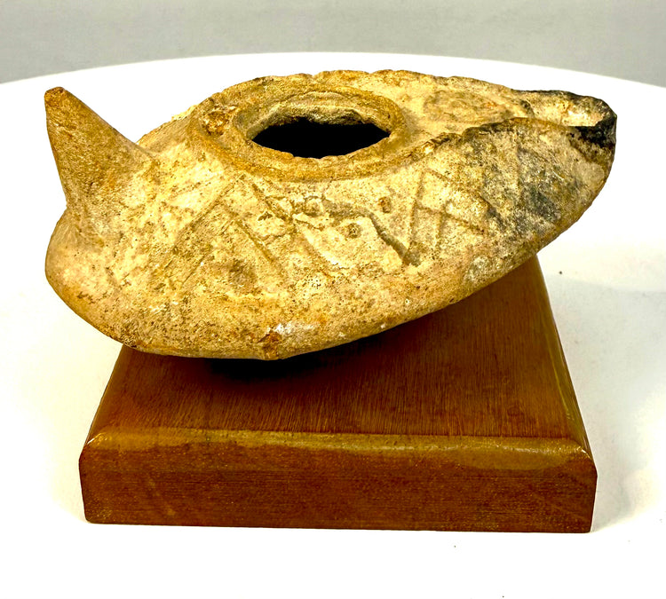 Late Antique Byzantine oil lamp with molded geometric patterns, weathered clay surfaces, and distinctive elongated nozzle.