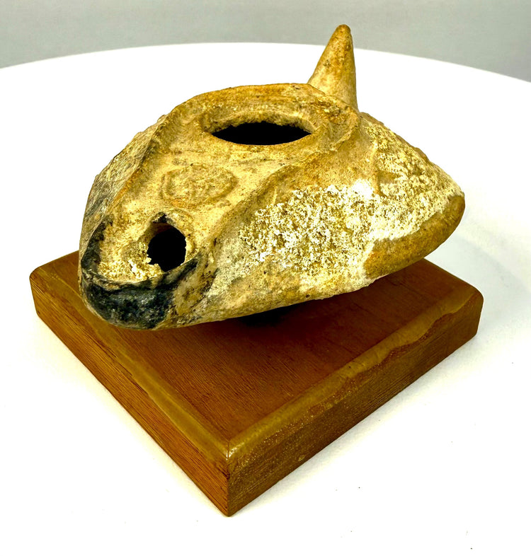 Byzantine terracotta oil lamp mounted on a rectangular wooden presentation base, featuring a raised filling rim and traditional slipper-shaped design.