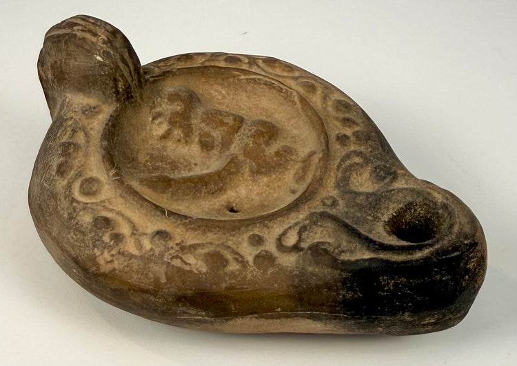 Roman Imperial terracotta oil lamp with erotic figural imagery, decorative circular motifs, and a projecting wick nozzle.