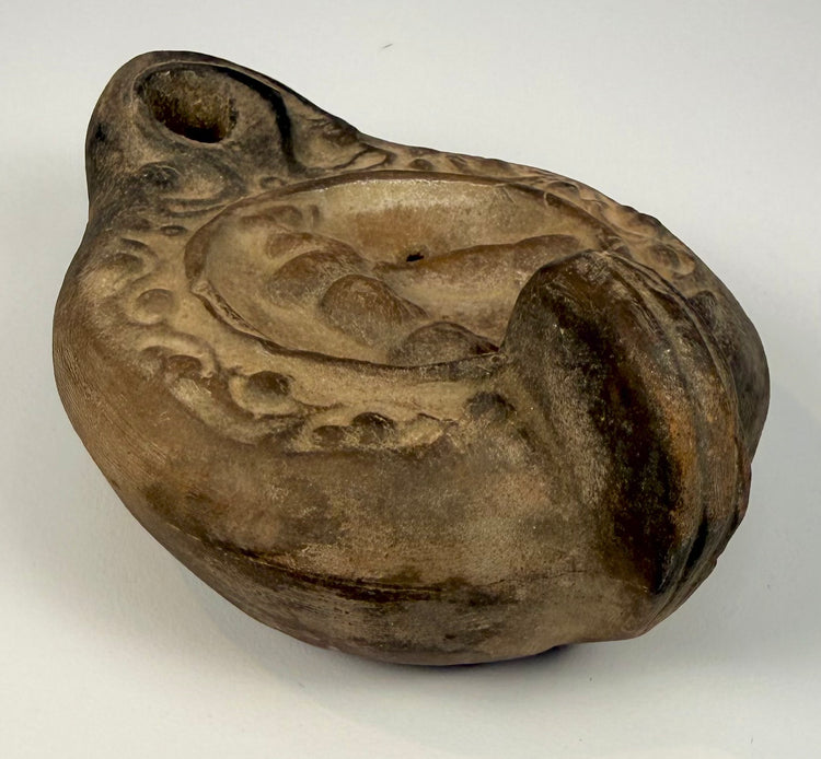 Roman terracotta oil lamp displaying concentric moulded borders, repeating oval patterns, and a recessed central discus.