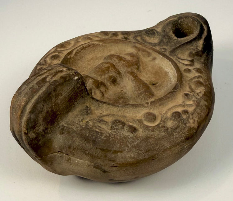 Ancient Roman ceramic oil lamp featuring a stylized male figure with exaggerated phallic anatomy and detailed relief ornamentation.