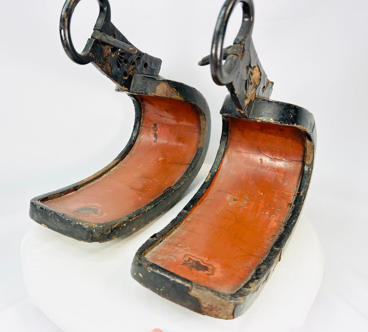 Pair of antique Japanese lacquered samurai stirrups with curved red interiors and black lacquered exteriors, Edo–Meiji period craftsmanship, displayed on a white background.