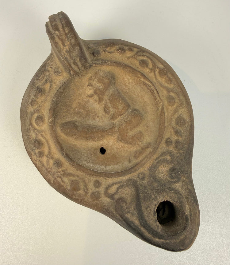 Ancient Roman terracotta oil lamp from the 2nd century CE, featuring ithyphallic symbolism, elaborate relief decoration, and characteristic Imperial Roman craftsmanship.