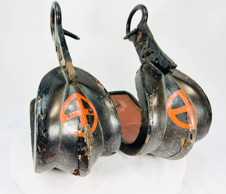 Pair of antique Japanese lacquered samurai stirrups with ornate cutout designs, red lacquer interiors, and cross-in-circle mon crests, Edo–Meiji period craftsmanship displayed on a white background.