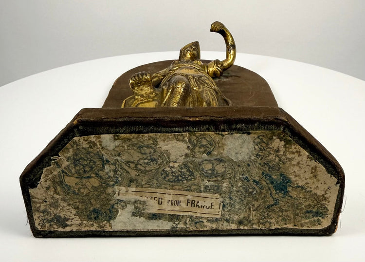 Reverse of an Italian gilt-bronze Minerva sculpture mounted on an arched wooden display stand with aged fabric covering, surface wear, and historical labels.