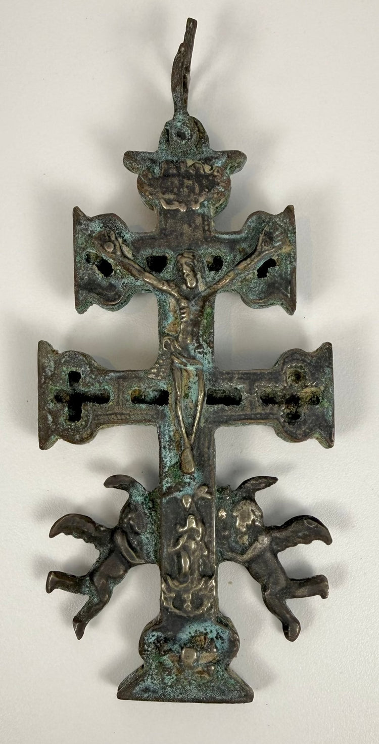 Spanish Cruz de Caravaca devotional cross with a raised figure of Jesus Christ, decorative pierced crossbars, and historic green patination.