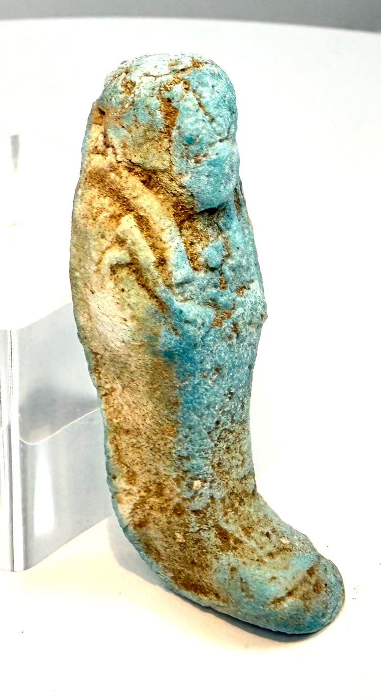 Egyptian faience ushabti with a stylized tripartite wig, softly modelled facial features, and surviving blue-green glaze with earthy deposits.