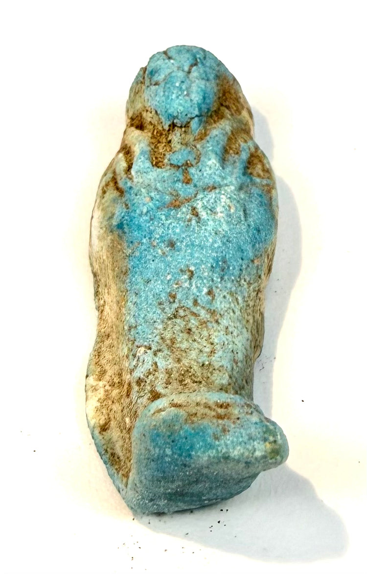 Late Period Egyptian ushabti figure displaying simplified facial details, a rounded headdress, and textured blue glaze with natural discoloration.