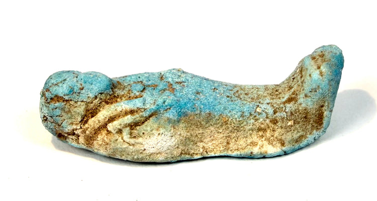 Turquoise-blue Egyptian ushabti funerary figure featuring softened facial modelling, localized glaze losses, fine cracking, and earthy-brown encrustations.