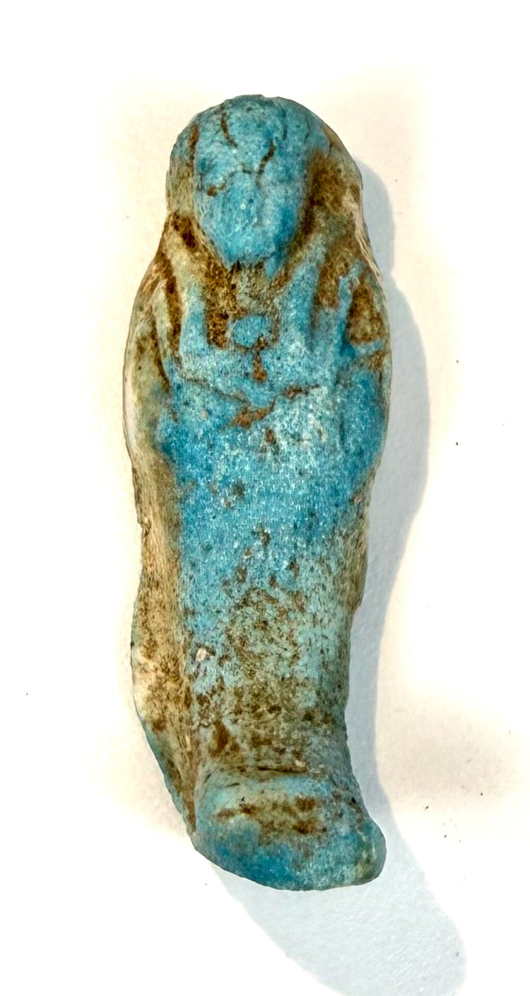 Egyptian faience funerary figurine displaying a comparatively plain reverse, softly rounded contours, and areas of surviving blue coloration.