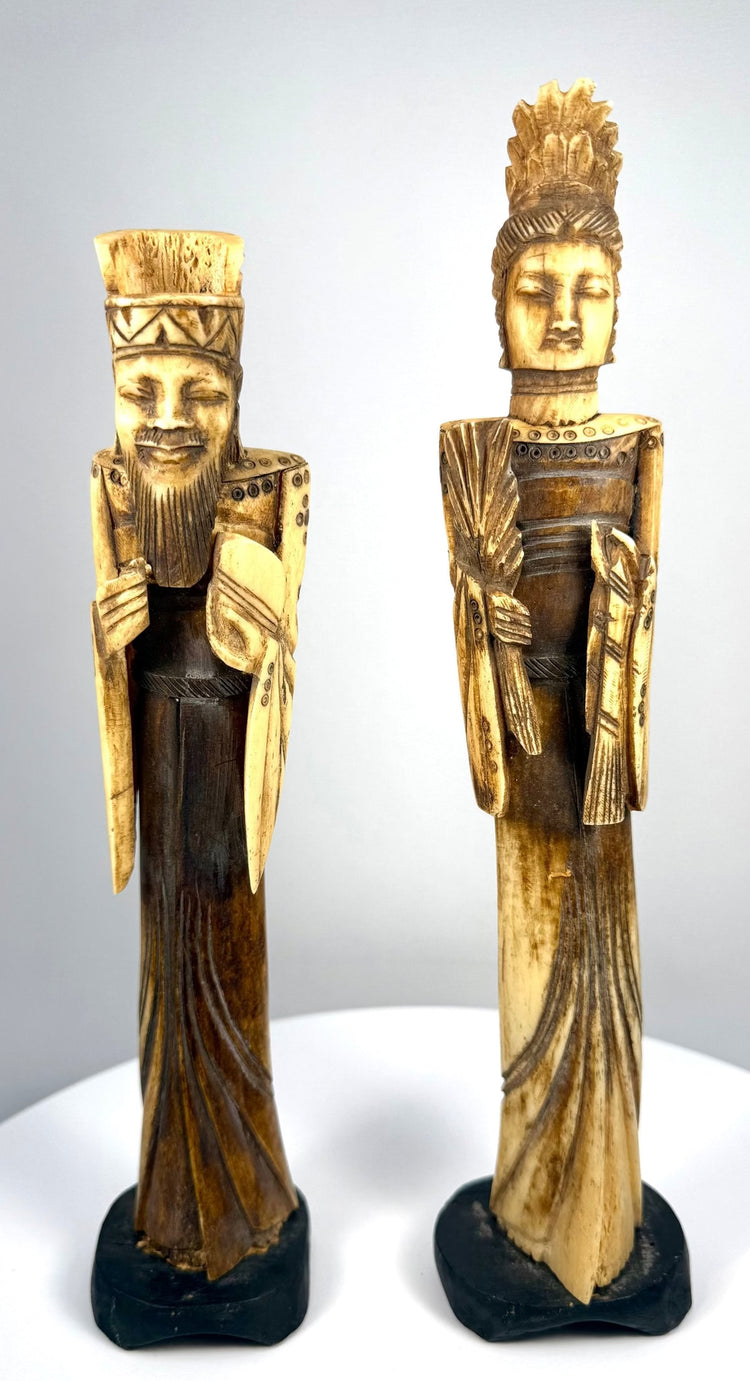 Matched pair of Chinese Emperor and Empress bone sculptures displaying slender proportions, detailed facial features, and contrasting cream and dark-brown surfaces.