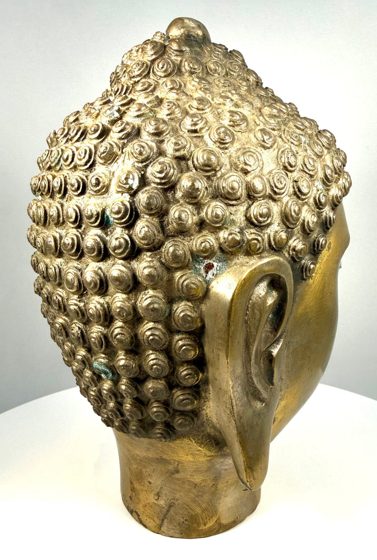 Mid-20th-century golden Buddha head statue with a contemplative smile, softly modelled lips, and intricate spiral hair detailing.