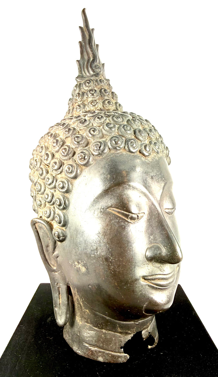 Traditional Thai Buddhist sculpture featuring extended earlobes, smooth facial contours, and a peaceful expression.