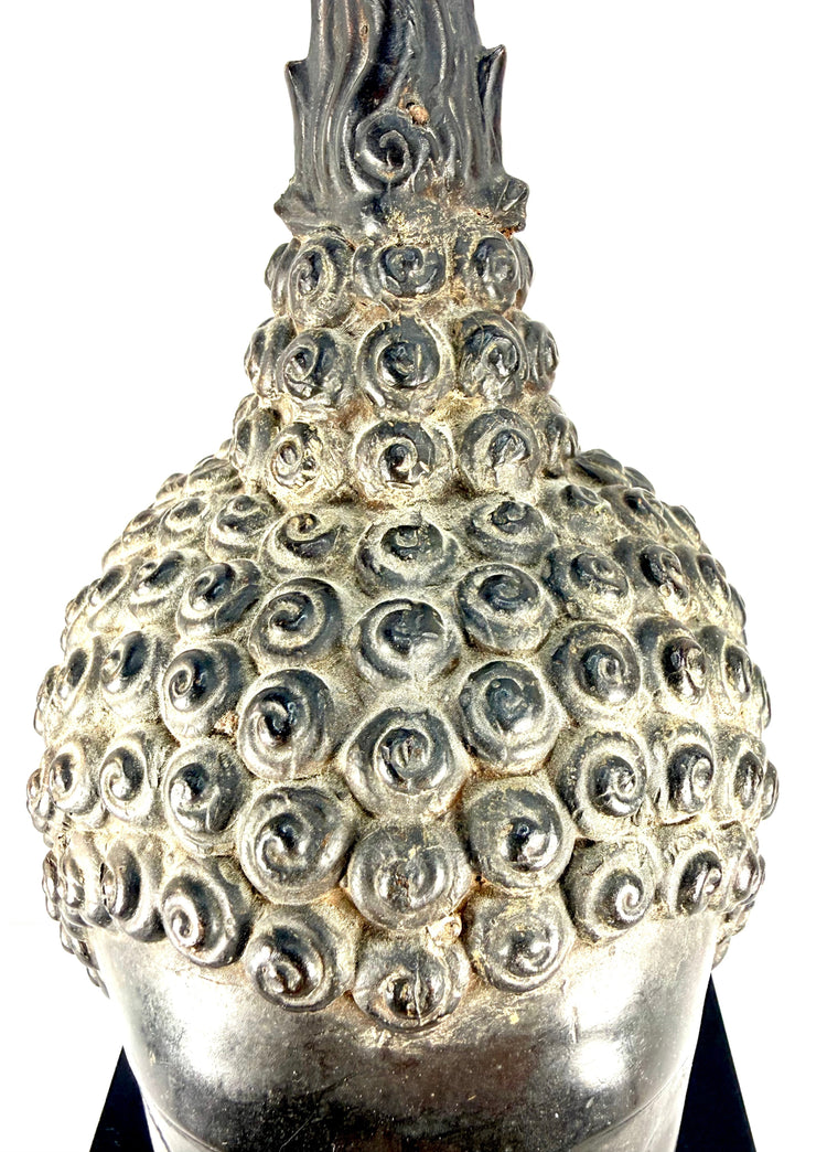 Cast copper-alloy Buddha head displaying dark grey-brown metallic patination and contrasting surface highlights.