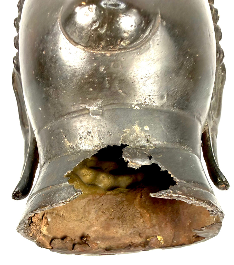 Antique Buddha sculpture showing an irregular opening, visible material loss, and age-related wear along the lower neck.