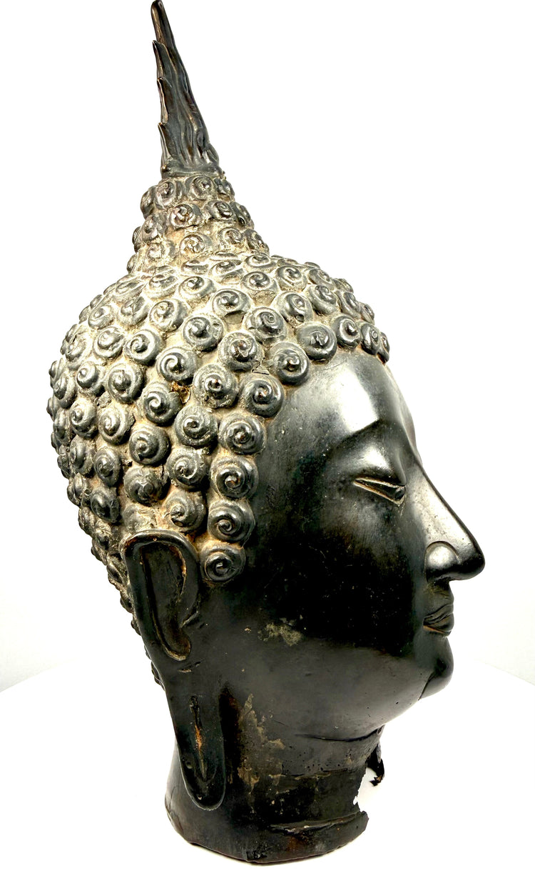 Antique Thai Buddha sculpture featuring a pronounced ushnisha crowned by an elaborate flame-shaped finial.