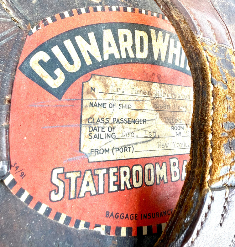 Early 20th-century leather top hat travelling case featuring an oval construction, stitched panels, and aged brown leather.
